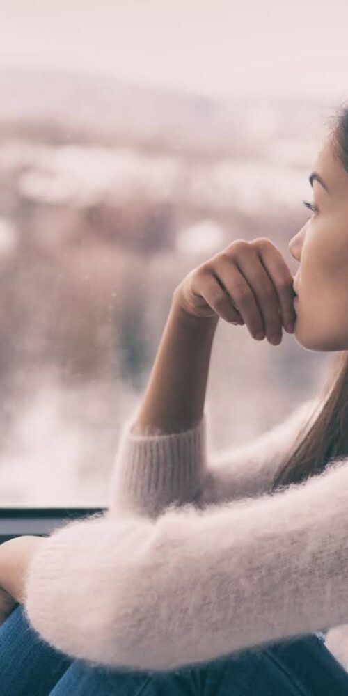 Woman looking out window in hopes of a depression cure. | Michigan Advanced Psych