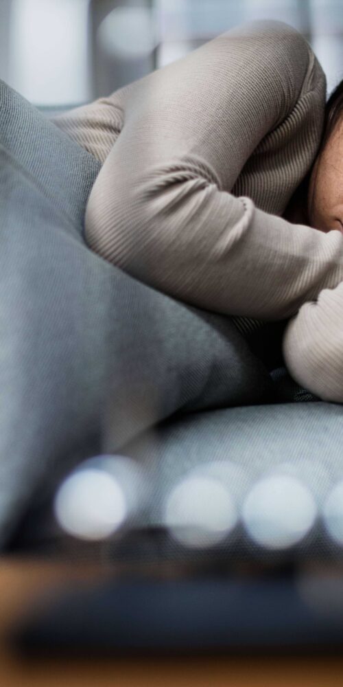 Woman lying on bed with sad eyes.